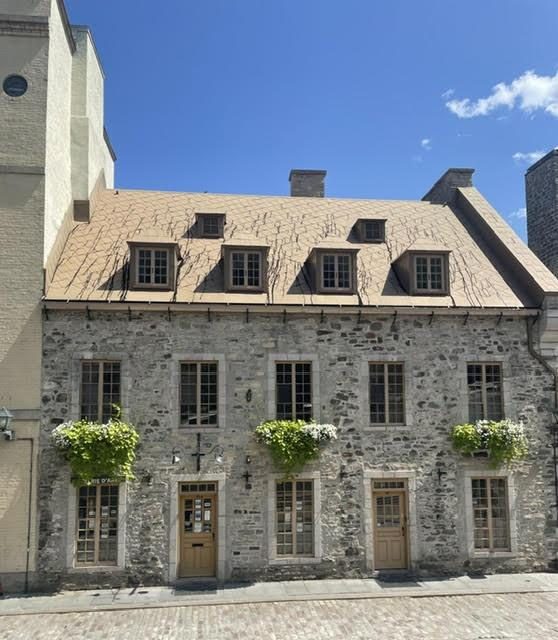 A stone building in Old Quebec topped with a traditional metal roof
